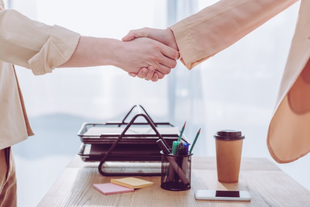 cropped view of employee and recruiter shaking hands in office